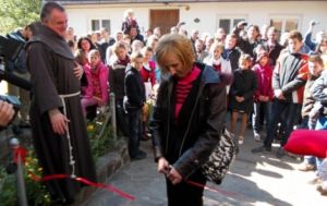 Palkó Cecília, a dévai gyermekotthon igazgatója vágja el a Szent Ferenc Alapítvány 20 évéről szóló kiállítás szalagját